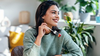 Woman smiling while eating healthy meal at home