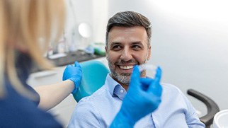 Patient smiling at dentist holding clear aligner