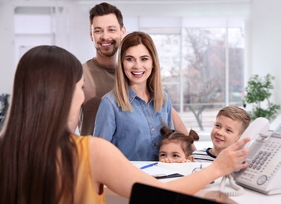 Family checkin in at dental office reception desk