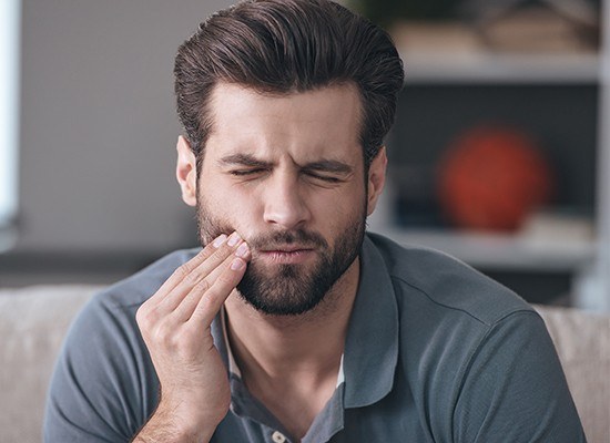 Man in pain holding cheek