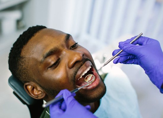 Dentist using instruments to examine patient's teeth