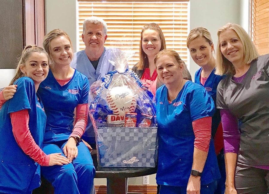 Dentist dental team members and patient posing with give away basket