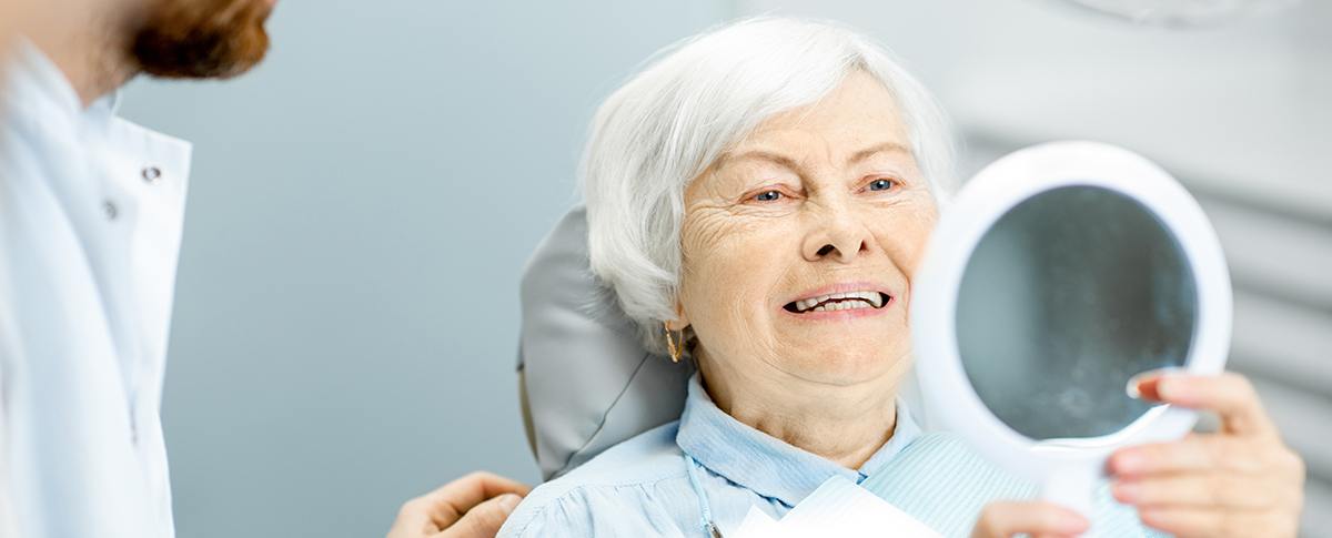 Older woman looking at smile in mirror