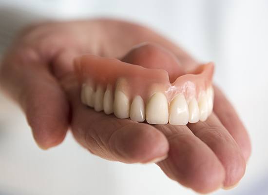 Hand holding a full denture