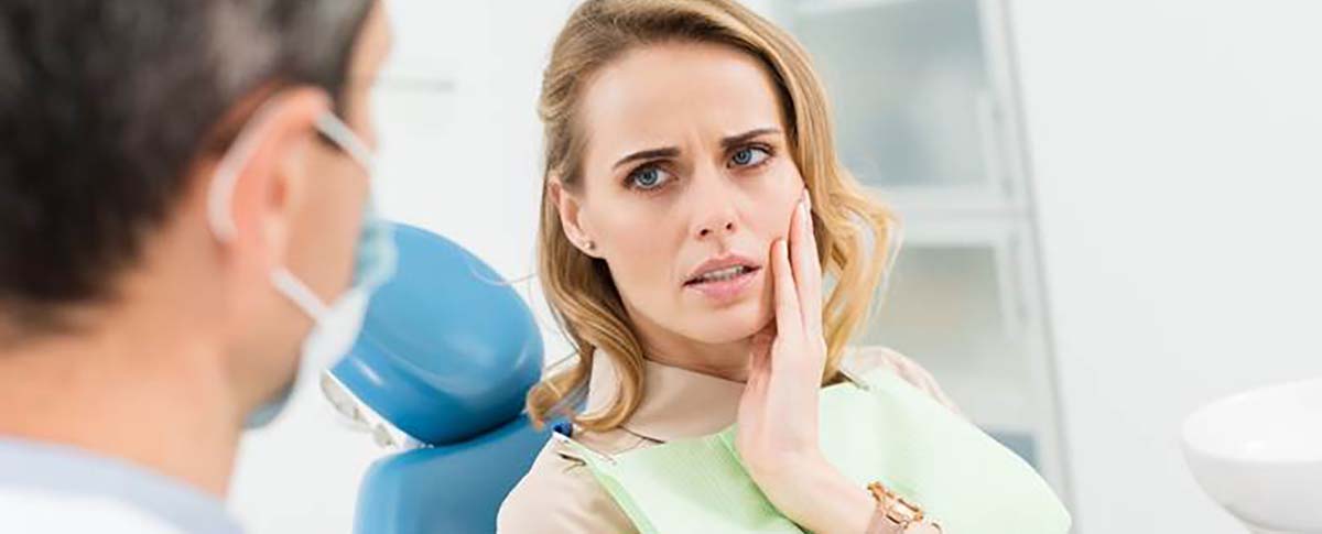 Woman with a toothache in Kingwood listening to dentist