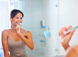 Woman brushing teeth ahead of visit to Kingwood emergency dentist