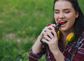 woman opening bottle with teeth