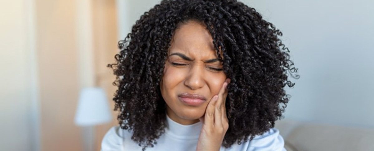 a woman holding her cheek due to dental implant failure  