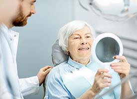 senior woman looking at her smile in a mirror