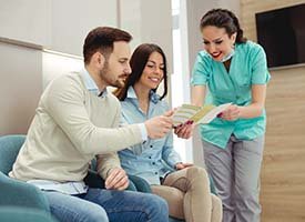 dental team member showing paperwork to two patients