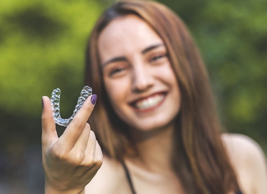 Woman holding Invisalign in Kingwood on green background