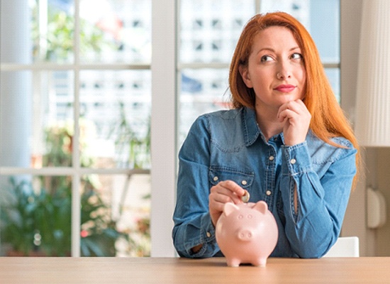 Woman putting coin in piggy bank for Invisalign in Kingwood