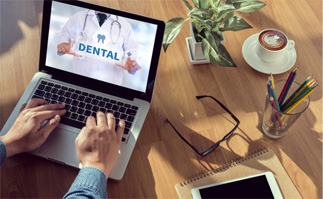 a person searching for dental insurance on a laptop” on a black keyboard