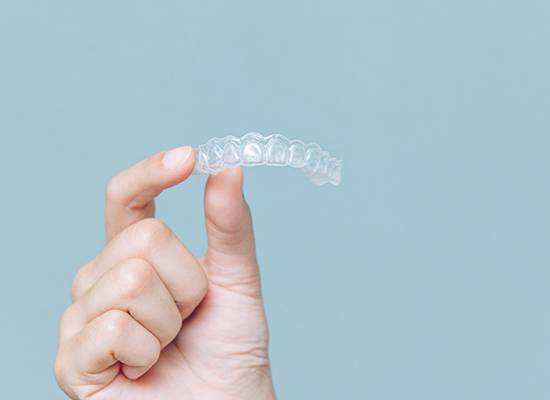 Patient holding up Invisalign in Kingwood