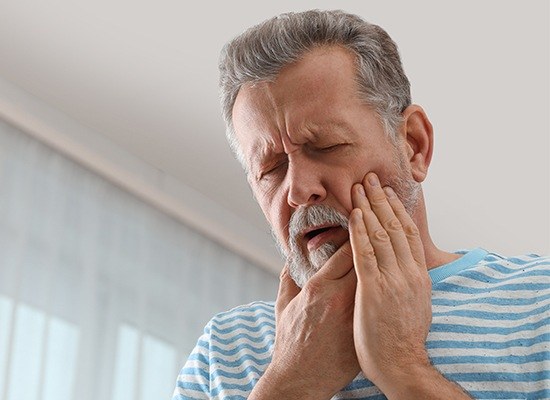 Older man holding jaw