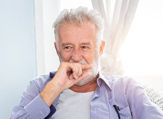 Older man covering his smile