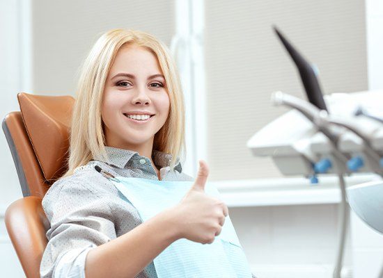 Woman in dental chair giving thumbs up