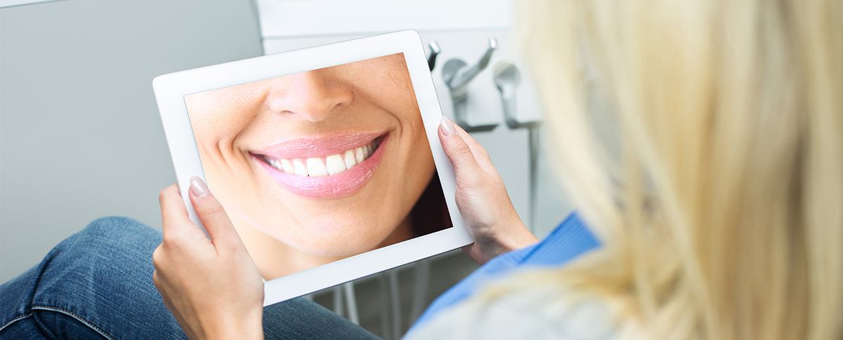 Woman looking at smile design on tablet computer