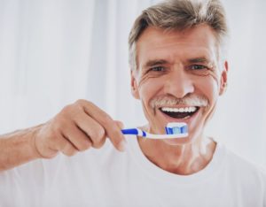 older man brushing his dental implants 