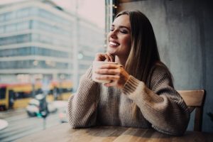 Woman in a coffee shop smiling and holding a mug