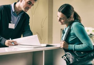 Happy female patient talking to dentist at front desk 