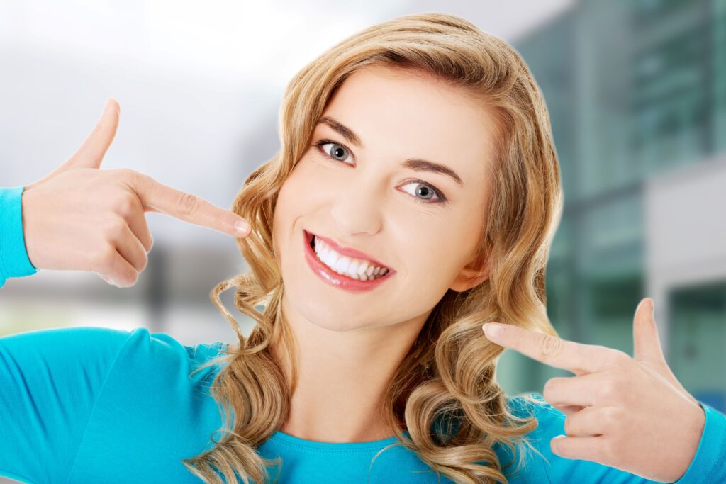 Woman pointing to her smile with both hands